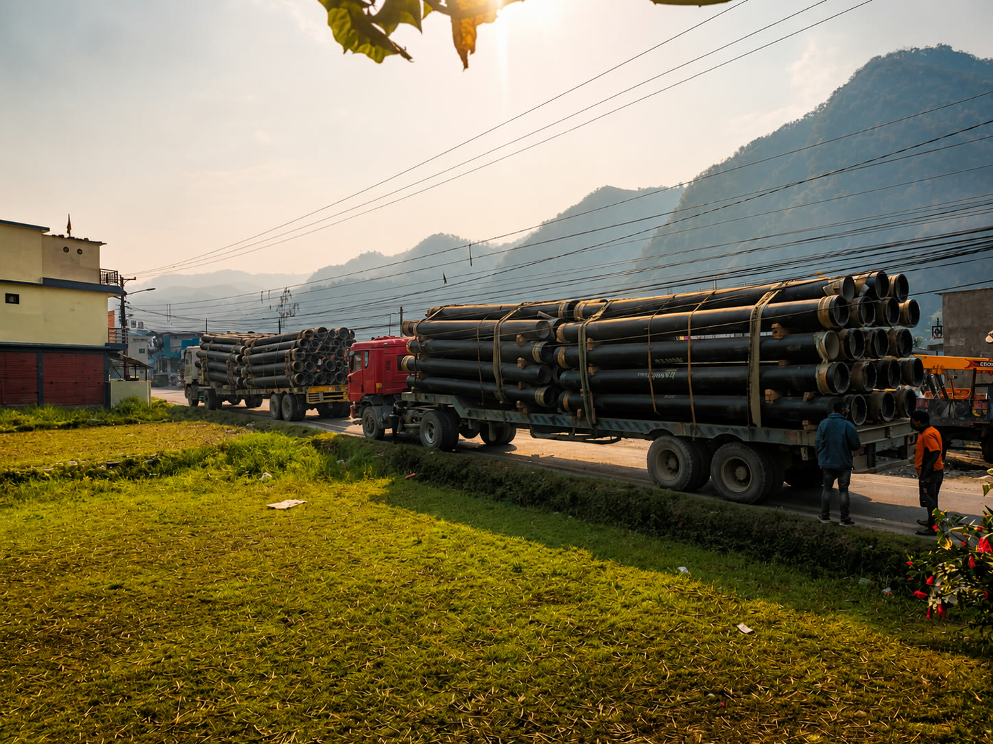 Two trucks carrying large pipe loads on a road